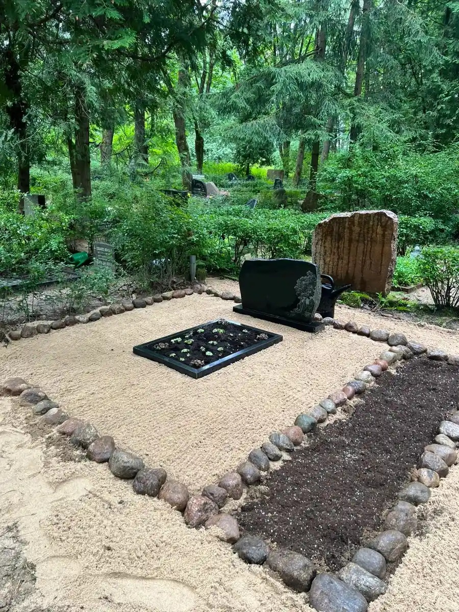 pabeigta kapavieta ar laukakmeņu perimetru un smilšu segumu